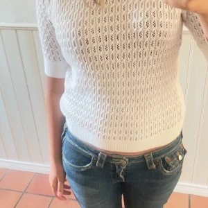 Vit stickad tröja från 157, XS - Vit stickad tröja från 157 i storlek XS. Tröjan har ett snyggt hålmönster, ribbade muddar och rund hals. Perfekt till jeans för en fräsch och chill look. Materialet är mjukt och andas, vilket gör den skön att bära under vår och sommar. Den är aldrig använd 