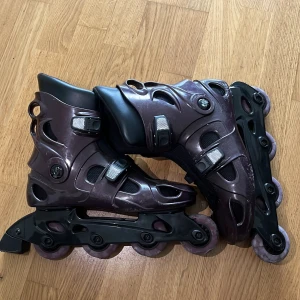 Mörklila inlines storlek 41/42 - Säljer ett par mörklila inlines med svart innerfoder och justerbara spännen. Skalet är i hårdplast och hjulen är lila med svart chassi. Perfekta för dig som vill cruisa runt i stan eller testa tricks i parken.
