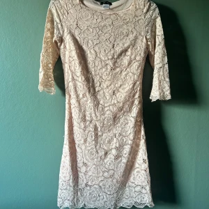 Ljus spetsklänning - Superfin ljus klänning i spets med blommigt mönster och trekvartsärm. Klänningen har en mjuk beige/rosa ton. Endast använd en gång på en bröllopsfest.