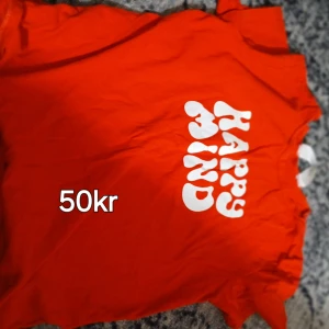 Orange t-shirt med tryck 'Happy Mind' - Snygg orange t-shirt med coolt vitt tryck där det står 'Happy Mind' på framsidan. Klassisk modell med korta ärmar och rund halsringning. Perfekt för dig som vill sticka ut med färg och positiv vibe.