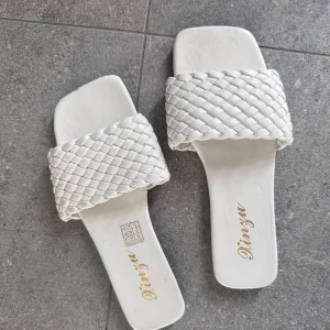 Vita flätade sandaler  - Snygga sandaler i vitt med bred, flätad rem över foten. Storlek 36