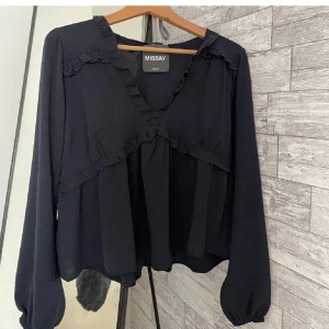 Mörkblå blus med volang från Missay - Supersnygg mörkblå blus från Missay med v-ringning och volangdetaljer längs halsringningen och över bysten. Långa ärmar med resår vid handlederna ger en luftig och avslappnad känsla. Perfekt för dig som gillar en feminin och trendig look.inte kvar prislappen på men jag har bara testat den