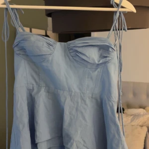 Ljusblå kort klänning från Zara - Supersöt ljusblå topp från Zara med tunna knytbara axelband och byst med rynkade detaljer. Knappt använt