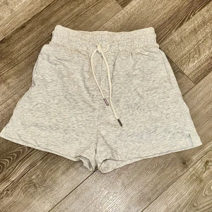 Grå mjuka shorts från H&M XS - Superbekväma ljusgrå shorts från H&M Basics med elastisk midja och snörning. Tillverkade i en mjuk bomullsblandning med polyester och viskos. Perfekta för chill dagar eller träning. Klassisk loose fit och enkel design utan mönster.