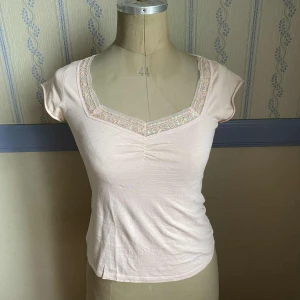 Ljusrosa topp med paljettkant  - Ljusrosa topp från Activewear med korta ärmar och lätt v-ringning. Använd sparsamt. Färgen är ljusrosa och stämmer bäst överens med bild 3. 🩷