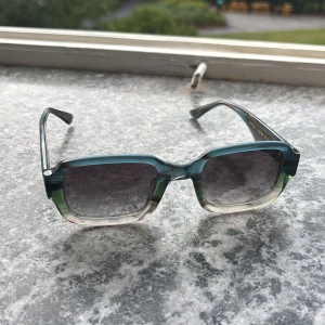 Rektangulära solglasögon från Vasuma - Snygga solglasögon från Malpolon med rektangulära bågar i transparent blågrön och beige toning. Tillverkade i Italien och designade i Sverige, eco-friendly material. Perfekta för dig som vill sticka ut med en cool och modern look.