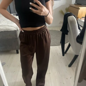Bruna vida byxor med resårmidja - Ginatricot storlek S. Säljer ett par bruna byxor med bred resår i midjan och rak, lite vidare passform. Byxorna har ett sammet liknande material. Aldrig använda. 