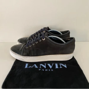 Marin blå  sneakers från Lanvin med lackad tå - Snygga marin blå  sneakers storlek 42 tror kan passa 43  från Lanvin Paris med ovandel i mocka och en glansig, lackad tå. Skorna har vita sulor, svarta snören och metallfärgade öljetter. Perfekt för dig som gillar stilrena men ändå unika detaljer.
