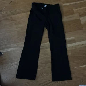 Svarta kostymbyxor från Lindex Kids - Svarta kostymbyxor från Lindex Kids i storlek 140. Byxorna har utsvängda ben och klassisk passform med knapp och dragkedja i midjan. Perfekta för dig som vill ha en stilren och enkel look. Justerbar midja!