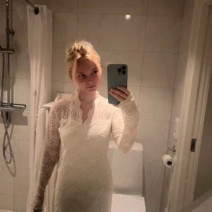 Vit spetsklänning med lång ärm - Supersöt vit kort spetsklänning med långa ärmar och v-ringad hals. Klänningen har genomgående spetsmönster och är figurnära med en feminin vibe. Perfekt för dig som vill sticka ut med en romantisk look. Säljes då den inte längre kommer till användning!