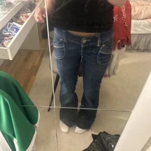 Mörkblå kick flare jeans från River Island - Säljer ett par mörkblå vintage kick flare jeans från River Island e med snygga fickdetaljer både fram och bak. Byxorna har låg midja och det är utsvängda. Säljer dessa pga att de är lite stora på mig💕pris kan även diskuteras. Jag har storlek W26 L30 och de är lite stora på mig