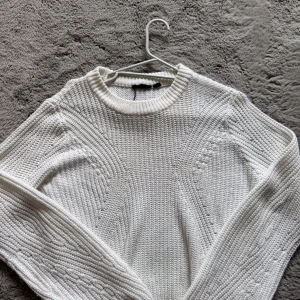 Vit stickad tröja med strukturmönster - Säljer en vit stickad tröja med snyggt strukturmönster och rund hals. Tröjan har långa ärmar och ribbade muddar vid hals, ärmslut och nederkant. Köpt på lager 157 och kommer inte alls till användning längre!