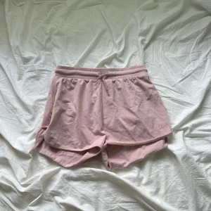 Ljusrosa shorts från WARR med snörning - Säljer ett par ljusrosa shorts från WARR i mjuk bomull. De har elastisk midja med snörning och rundade kanter för en sportig vibe. Perfekta för sommardagar eller träning. Superbekväma och lätta att matcha med en enkel t-shirt eller hoodie.