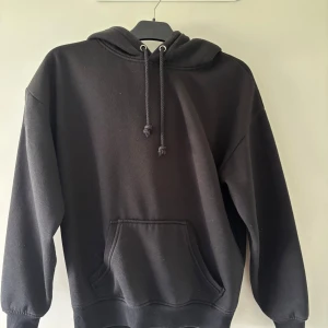 Svart hoodie från BikBok XS - Klassisk svart hoodie från BikBok i storlek XS. Tröjan har huva med snörning, magficka och ribbade muddar vid ärmslut och nederkant. Perfekt för en chill och avslappnad stil.