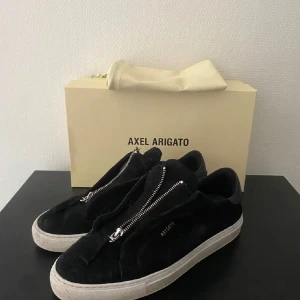 Svarta sneakers Axel Arigato mocka - Svarta sneakers från Axel Arigato i mjuk mocka med cool dragkedja.