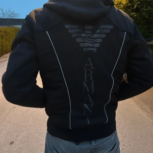 Svart Armani bomberjacka - Svart bomberjacka från Armani med stor logga och text på ryggen.