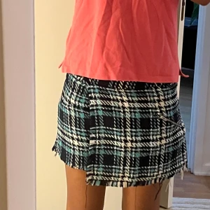 Rutiga omlottshorts från Zara - Snygga rutiga shorts från Zara i omlottmodell med fransad kant. Färgerna är svart, vit och turkosblå. Är i barnstorlek 164 men kan sägas vara ca xs! Skriv för fler detaljer!❤️