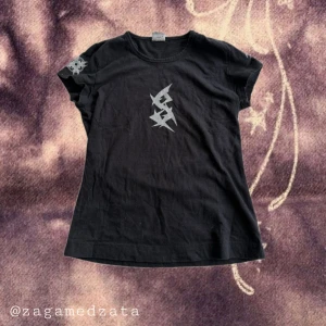 Svart band-tshirt Sonar Peggy S - Svart t-shirt från Sonar i modellen Peggy med coolt silvertryck på bröstet och ärmen samt texten 'Secrets of the Moon' på ryggen. Klassisk rund hals och korta ärmar. Perfekt för dig som gillar bandmerch och edgy stil.