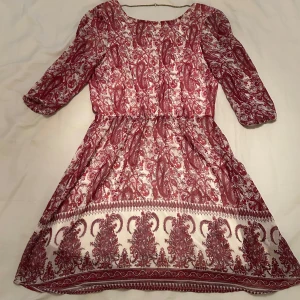 Rödvit mönstrad klänning BikBok - Supersöt kortklänning från BikBok i rött och vitt med blommigt mönster. Djup v-ringning i ryggen med kedjedetalj. Storlek Xs