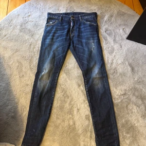 Blå jeans från Dsquared2 - Snygga blå jeans från Dsquared2 i klassisk skinny fit. Jeansen har slitna detaljer, fem fickor och tydliga kontrastsömmar. Tillverkade i jeansmaterial med en mörkblå tvätt och diskreta slitningar för en cool look.