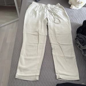 Petite beiga linnebyxor med snörning - Snygga och luftiga beiga linnebyxor med elastisk midja med snörning. Perfekta för varma dagar och ger en avslappnad vibe. Materialet är linne som känns svalt och skönt mot huden.