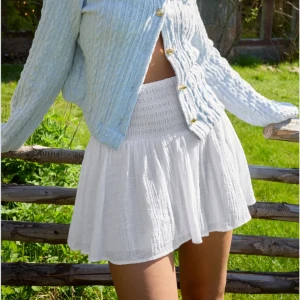 Kort kjol från Nelly🤍 - Superfin vit kortkjol från Nelly i luftig linnemix. Kjolen har smockad midja och lätt volang nedtill för en söt och avslappnad vibe. Kjolen har en liten fläck på framsidan som syns på bild 5 annars är den i mycket fint skick!!🤍😊 