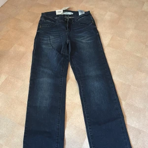 Mörkblå jeans Eleven från Vero Moda - Snygga mörkblå jeans från Vero Moda, modell Eleven. Regular fit med normal midja och klassisk femficksdesign. Jeansen är i stretchigt denim och har subtila slitningar framtill för en cool look. Perfekta till sneakers eller boots.