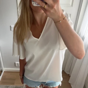 Vit blus Vila - Superfin vit blus från Vila med v-ringning och korta ärmar. Lätt och luftigt material. Strl 36 ochr normal i storlek.