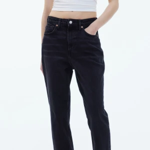 Straight svarta jeans - Snygga svarta jeans med hög midja och raka ben. Jeansen har klassisk femficksdesign, bälteshällor och knappgylf. Perfekta till en crop top eller hoodie för en chill look.