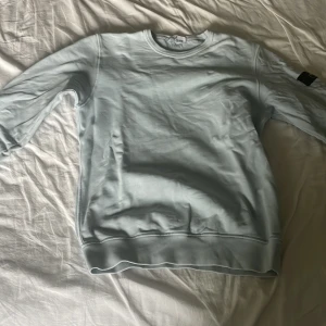 Ljusblå sweatshirt från Stone Island - Säljer en ljusblå stone Island sweatshirt i top top skick inga skavanker. Säljes pga att jag inte använt den på ett bra tag o tröttnat på tröjan. Tröjan är i storlek 170 men passar även större passar även mig som är ca 175. Hör av er vid frågor eller om ni vill ha bättre bilder så löser vi det!