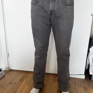 Grå raka jeans - Säljer ett par grå jeans med raka ben och klassisk femficksdesign. Jeansen har normal midja och är tillverkade i mjukt denimtyg. Perfekta för en avslappnad och stilren look.