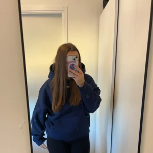 Mörkblå oversized hoodie Paranoid - Säljer en mörkblå oversized hoodie med stor huva och trycket 'PARANOID' i vitt på ryggen. Hoodien har en klassisk känguruficka framtill och långa ärmar. Perfekt för dig som gillar streetwear och vill ha en chill look.