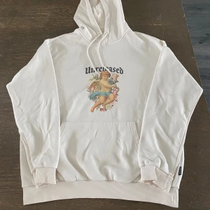 Beigevit hoodie med ängeltryck från YOURTURN - Snygg beigevit hoodie från YOURTURN med tryck av en ängel och texten 'Unreleased' på bröstet. Liten fläck på axeln (se bild)
