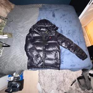 Polo Ralph lauren vinterjacka  - Svart Ralph lauren jacka som är perfekt av slutet av hösten och hela vintern. Har en luva som man kan ta bort vid behov. Flera olika fickor även vid bröstet. Såklart rikigt! Hör bara av er om ni har några frågor eller funderingar. Är ganska stor i storlek så passar både XS och S!