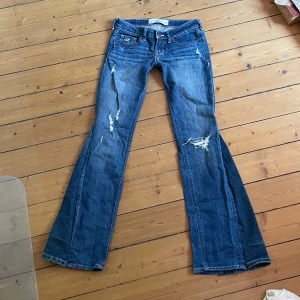 Mörkblå lågmidjade bootcut jeans - Säljer dessa jätte snygga mörkblå lågmidjade jeans med slitningar på benen som tyvärr är försmå för mig. Märket på jeansen är hollister och de är utsydda till bootcut. Midjemått 33 cm tvärs över midjan och innerbenslängden 72 cm. Kontakta mig privat vid frågor eller liknande 💕. Säljer även fler jeans i min profil 