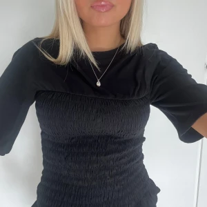 Svart smockad topp med volang - Säljer en supersnygg svart topp med smockad midja och volangkant nedtill💋💋