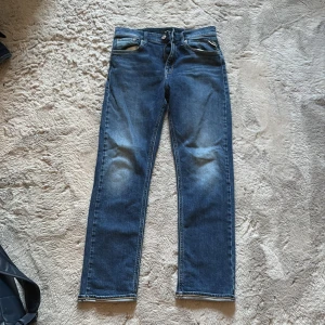 Blå jeans från Replay, rak modell - Säljer ett par klassiska blå jeans från Replay i rak modell. Jeansen har snygga slitningar framtill, fem fickor och dragkedja. Perfekta för dig som gillar en tidlös look och vill ha ett par jeans som funkar till det mesta.