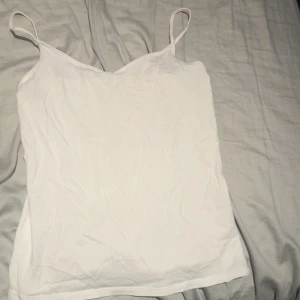 Vit linnetopp från Cubus, storlek M - Enkel och stilren vit linnetopp från Cubus i storlek M. Toppen har tunna axelband och är tillverkad i bomull. Snygg att styla med jeans eller kjol för en clean look.
