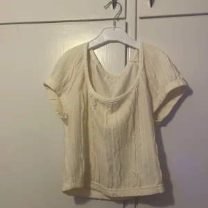 Krämvit blus från SHEIN, S - Krämvit blus från SHEIN i storlek S. Toppen har korta ärmar, rund halsringning och ett lätt skrynklat tyg som ger en avslappnad vibe. Tillverkad i polyester med en luftig känsla, perfekt för varmare dagar. Köpte för ca 100kr och säljer för 30kr💕