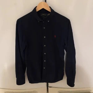 Mörkblå skjorta från Polo Ralph Lauren - Säljer en stilren mörkblå skjorta från Polo Ralph Lauren i. Skjortan har långa ärmar och knappar framtill. Perfekt för skolstarten! Den är i mycket bra skick. Passar perfekt till alla årstider. Nypris 1800