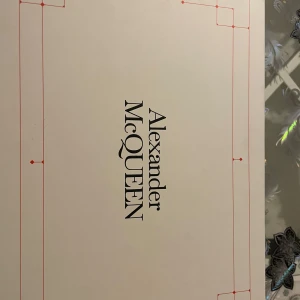 Svarta sneakers från Alexander McQueen - Stilrena svarta sneakers från Alexander McQueen med vita detaljer och logga på hälen. Skorna har tjock sula, rund tå och breda snören med svartvitt mönster. Tillverkade i skinn för en lyxig känsla och passar perfekt till en trendig streetwear-look. Kvitto och box finns, säljer för använder inte dem. Storlek 