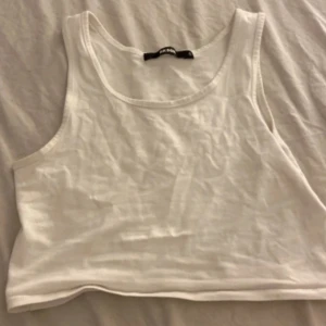 Vit croppad linnetopp från Bik Bok - Enkel och fräsch vit croppad linnetopp från Bik Bok. Modellen är ärmlös med rund halsringning och tillverkad i mjuk bomull. Perfekt att matcha med jeans eller kjol för en clean look.