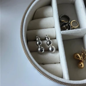 Silvriga örhängen med kulor - Säljer ett par coola silvriga örhängen med tre runda kulor i olika storlekar på varje örhänge. De har en modern och minimalistisk vibe och är perfekta för att ge din look lite edge. Passar dig som gillar statement-smycken och stilrena detaljer.