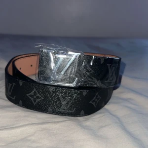  svart skärp med monogram - Svart bälte i skinn med klassiskt monogrammönster och stor silverspänne Bältet har en lyxig känsla och är perfekt för att lyfta vilken outfit som helst!