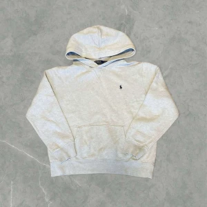 Grå hoodie från Polo Ralph Lauren - Säljer en stilren grå hoodie från Ralph Lauren med den klassiska broderade loggan på bröstet. Den är i toppen skick, endast använd ett fåtal gånger. Storlek 14/16 barnstorlek vilket motsvarar en S. Vid några frågor eller funderingar är det bara att höra av sig.