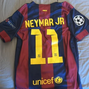 FC Barcelona Neymar JR 11 matchtröja - Säljer en FC Barcelona matchtröja med Neymar JR och nummer 11 på ryggen. Tröjan är kortärmad, har breda marinblå och röda ränder, Champions League-patch på ärmen och Qatar Airways som sponsor. Tillverkad i lätt Dri-FIT polyester för bästa komfort.