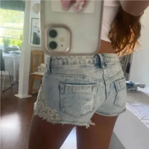 Ljusblå lowwaist jeansshorts med spetsdetaljer - Snygga low waist jeansshorts i strl 37, midja:42. Kommer fler unika jeansshorts/kjolar så följ!!