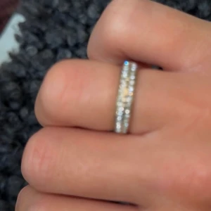 Glittrig guldfärgad ring med stenar  - Snygg ring med två rader glittrande stenar som ger riktigt mycket bling. Ringen har en mix av guld och silverton och är rund i formen. Perfekt för dig som vill ha något som sticker ut och glänser extra mycket.