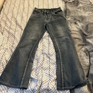 Bootcut jeans med broderade fickor Romwe - Snygga bootcut jeans från Romwe i mörkblå tvätt med broderade bakfickor. Jeansen har klassisk femficksdesign och vida ben nertill. Materialet är jeans och passformen är normal. Perfekta för dig som vill sticka ut med detaljer på fickorna.