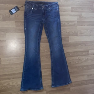 Blå flare jeans Ultra Low Rise, stl 27 - Snygga blå jeans från True Religion i modellen Ultra Low Rise Flare. Jeansen har låg midja, utsvängda ben och klassiska kontrastsömmar samt broderad bakficka. Tillverkade i mjukt denim med lätt tvättad look. Priset kan diskuteras💞